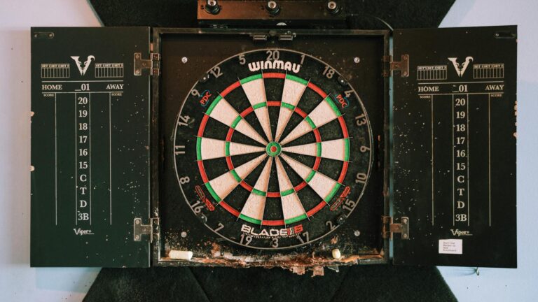 Mit Augen-Dominanz beim Darts das Ziel präzise anvisieren und treffen Dartspieler zielt konzentriert mit dominantem Auge auf das Dartboard