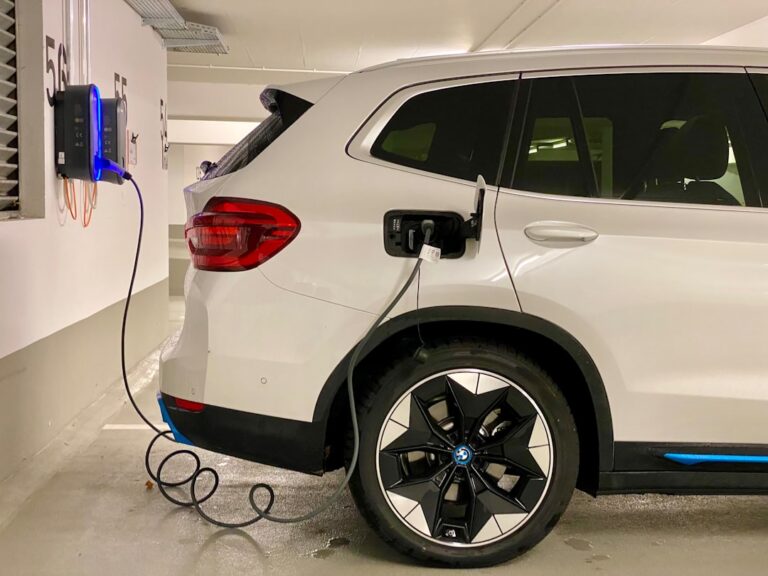 Wallbox an Hauswand installiert mit Elektroauto und Fördermittelinfo im Hintergrund
