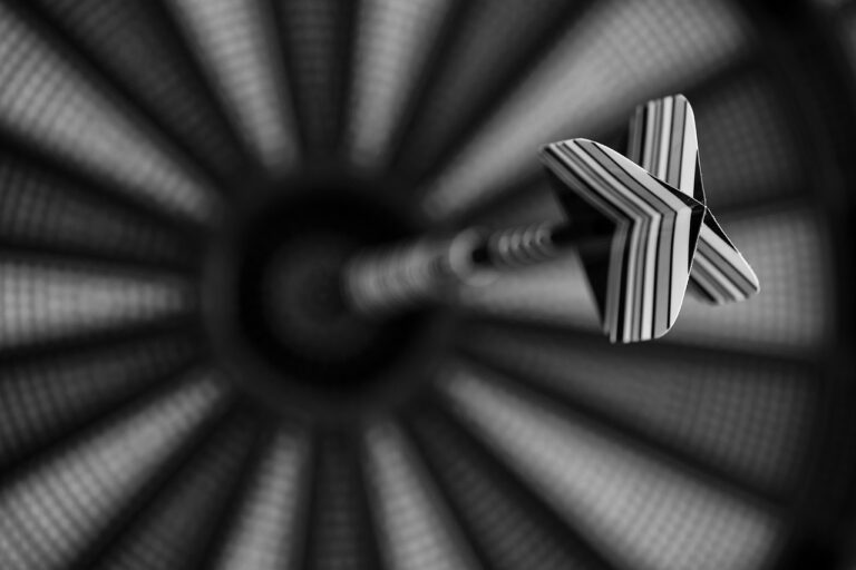 Präzises Werfen leicht gemacht mit zielen Anfänger Darts Anleitung Anfängerin zielt konzentriert mit Dartpfeil auf Dartscheibe beim Training